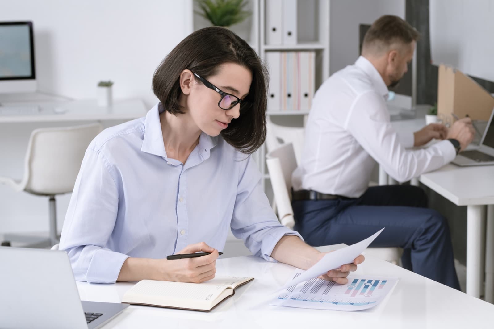 Controller reviewing approval paperwork and charts at her desk